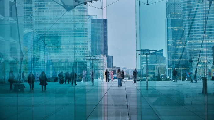 Workers walk through the Grande Arche office block at the end of the day in the La Defense business district, in Paris