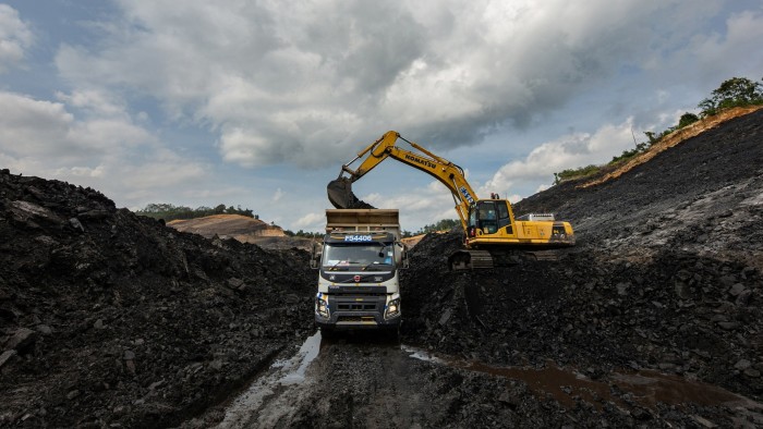 An excavator loading coal on to a dump truck at an open-pit mining site