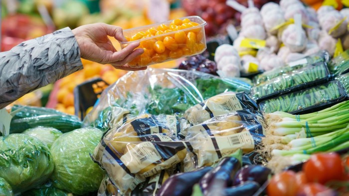 The hand of a shopper picking fruits and vegetables at an indoor market