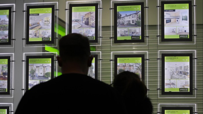 People looking at the signs in an estate agent’s window in London