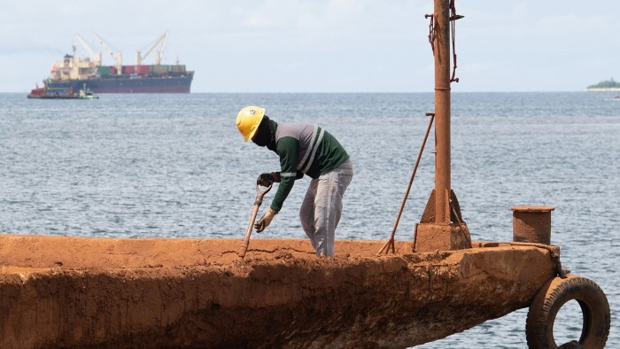 A worker shovels nickel ore minerals at a pier in the village of Rio Tuba, Palawan province