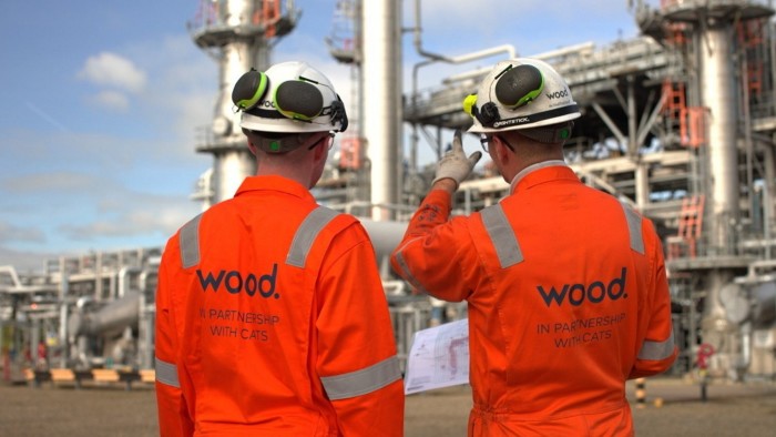 Two employees wearing high-visibility coveralls and hard hats on a Wood Group site