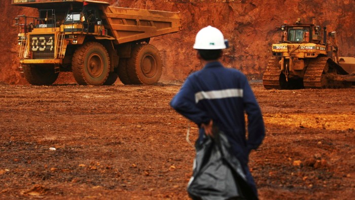A worker watches as trucks load up raw nickel near Sorowako on Indonesia’s Sulawesi island
