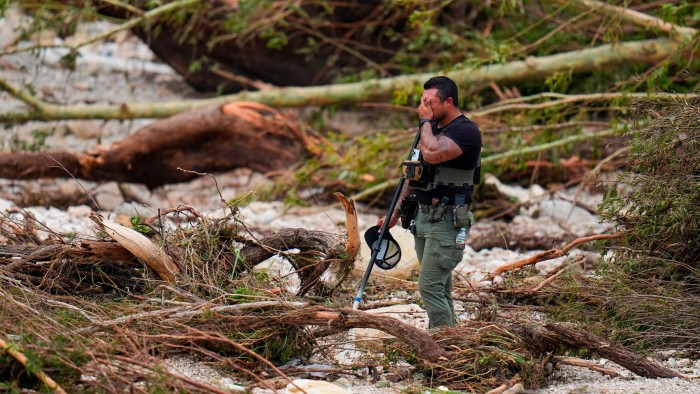 A sheriff’s deputy pauses while combing through the banks of the Guadalupe River near Camp Mystic
