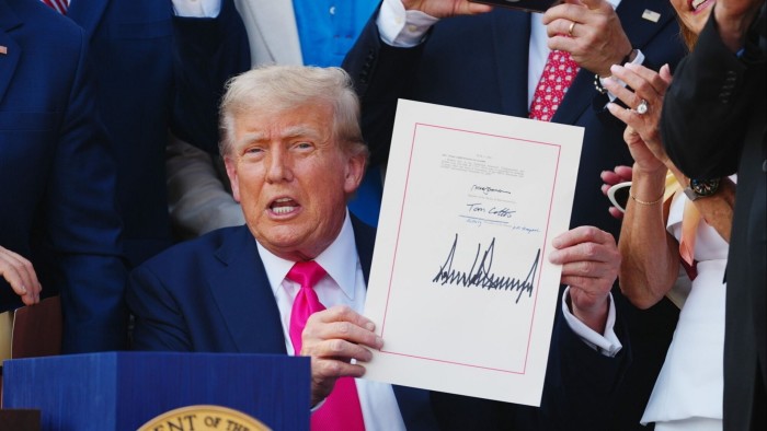 Trump holding up signed copy of his tax and spending bill