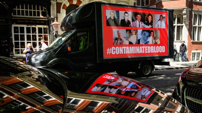 A digital screen displays a poster publicising the fight for justice by those infected by tainted blood