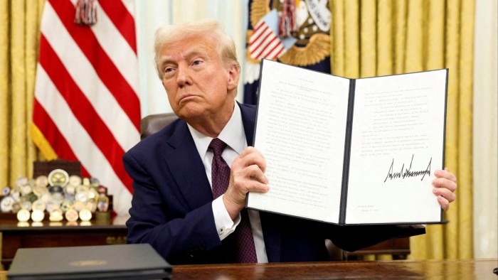 US President Donald Trump holds a signed executive order in the Oval Office of the White House
